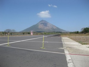 The road crosses the airport runway with St Christobal volcano reigning int he background